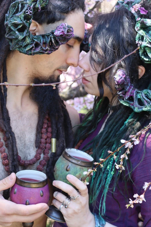 a man and woman kissing holding vases in a forest