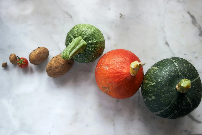 five oranges, two lemon, and one green pumpkin are on the marble table