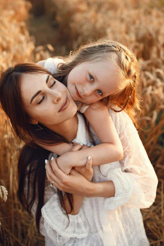 a woman hugs her daughter in a field of tall grass