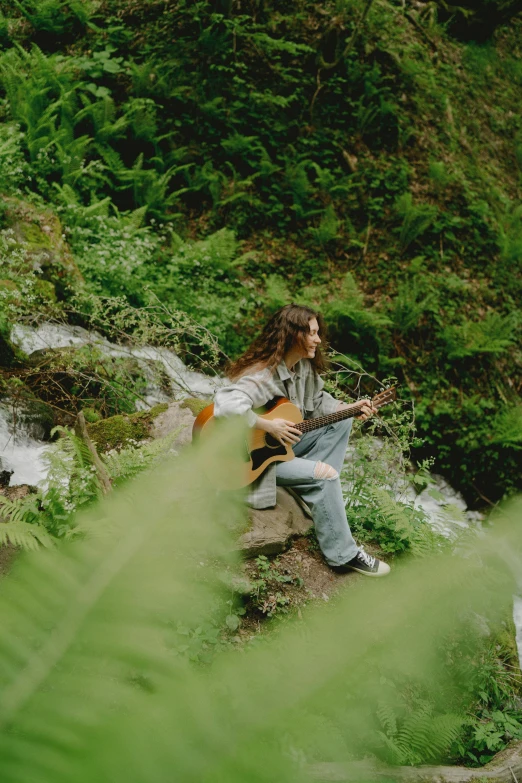 a person that is sitting on a bench playing the guitar