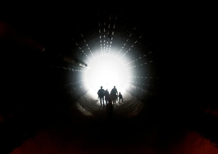 several people ride bicycles inside of a tunnel