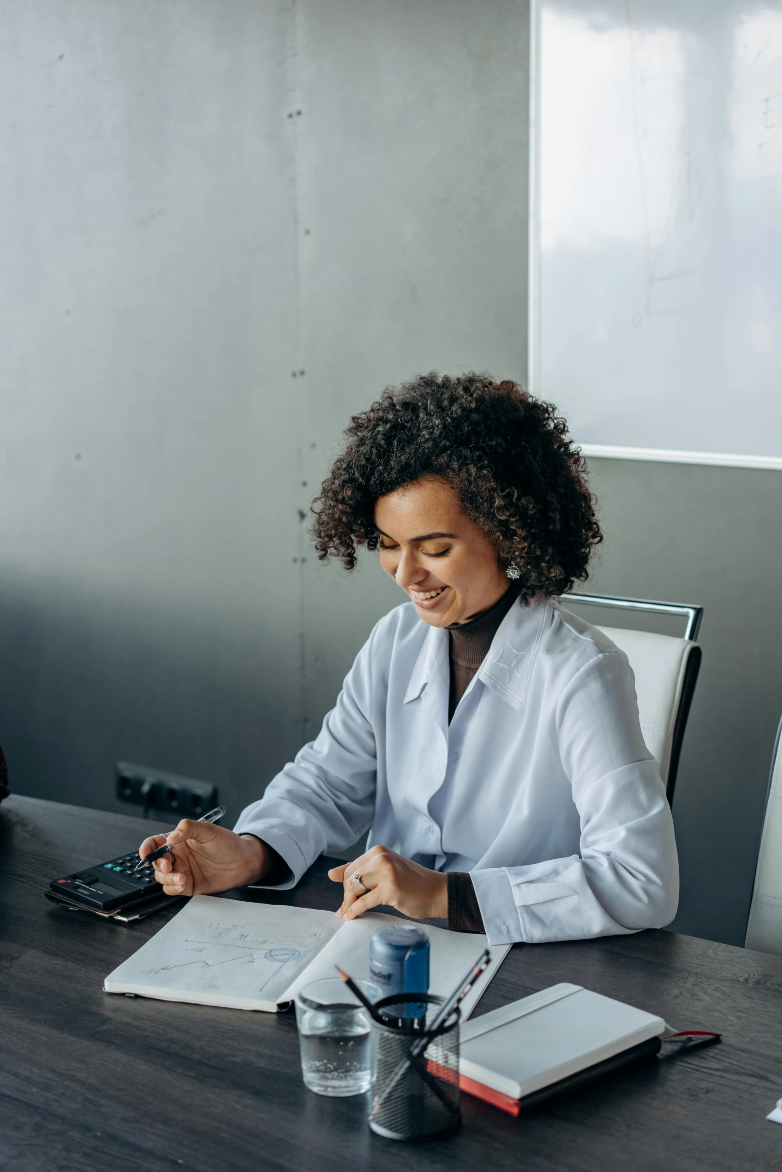 a woman sitting at a table in a conference room doing soing