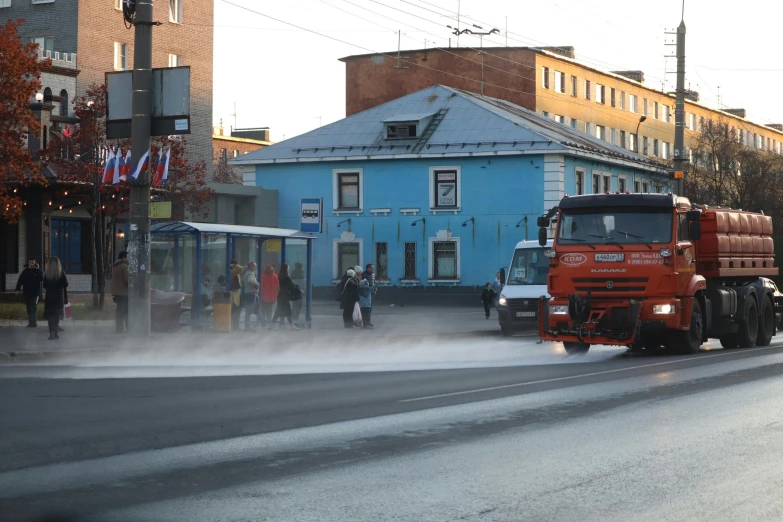 a red truck driving down a street next to houses