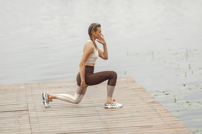 a woman is standing on the end of a wooden dock and listening to music