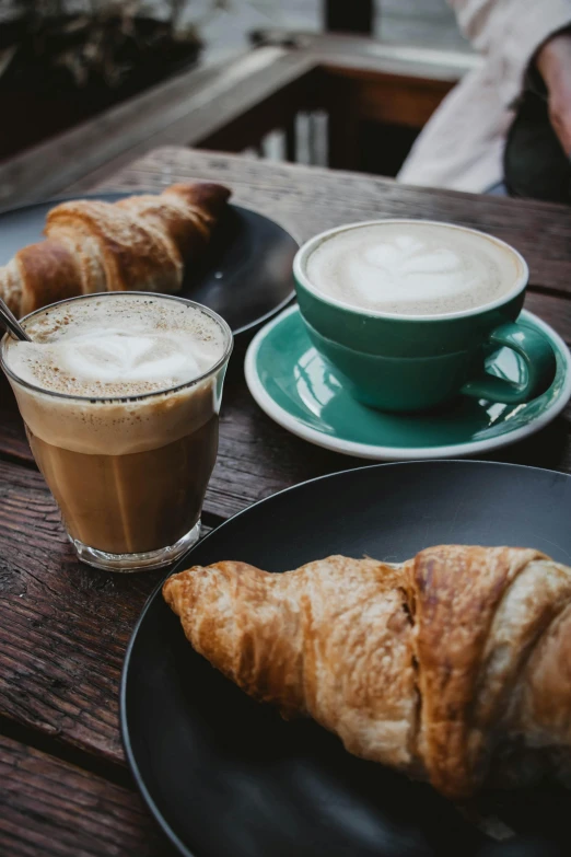 pastries on a black plate, coffee cups, and a croissant