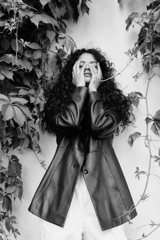 a woman is posing near some plants and posing for the camera