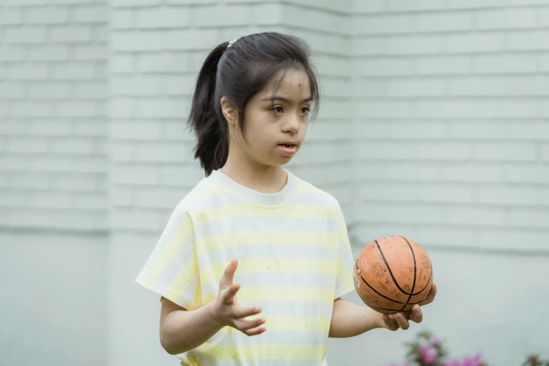 the small child holds up a basketball while she's ready to hit it
