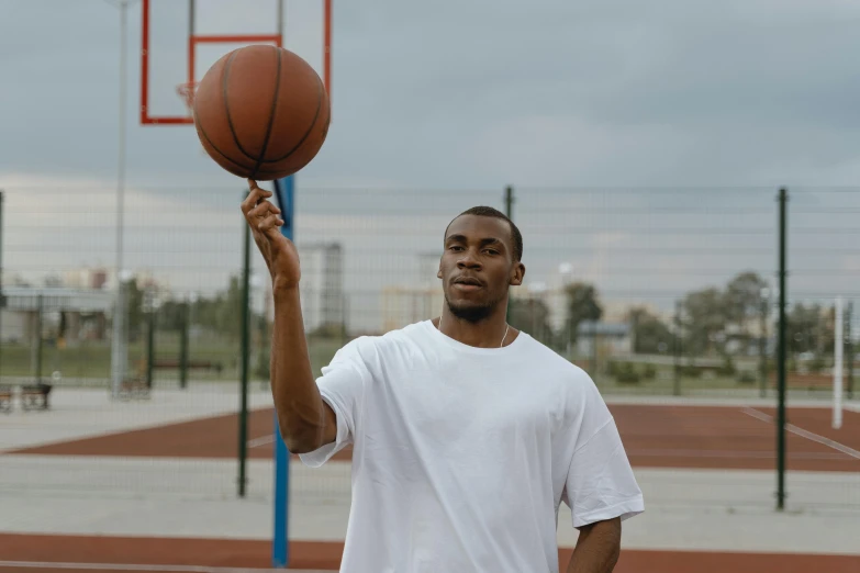 a young black man holding a basketball at the court