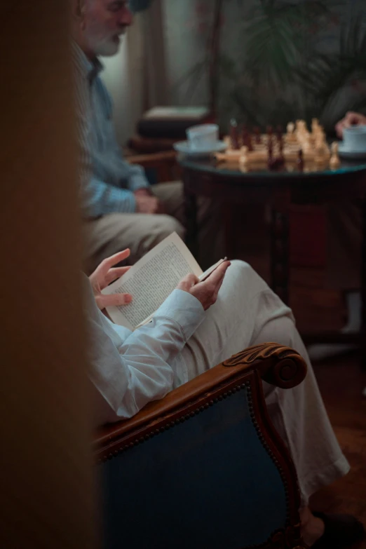 a man is sitting on a chair with his hands resting on a book in front of him