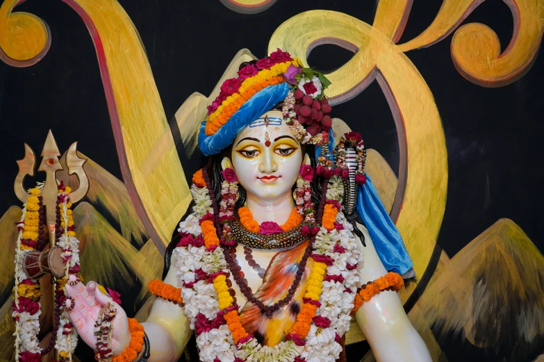 statue in front of wall decorated with paintings and gold