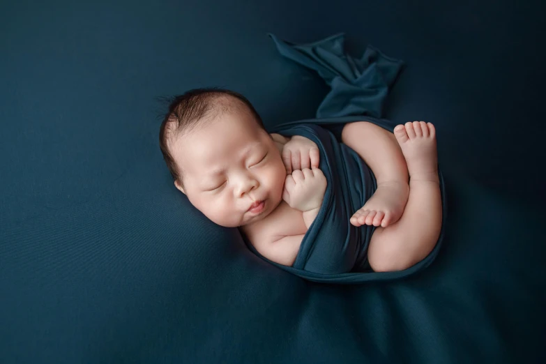 a baby laying on its back wearing a blue wrap