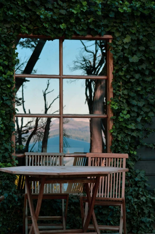 a wooden table sits on the patio under an old window with a view