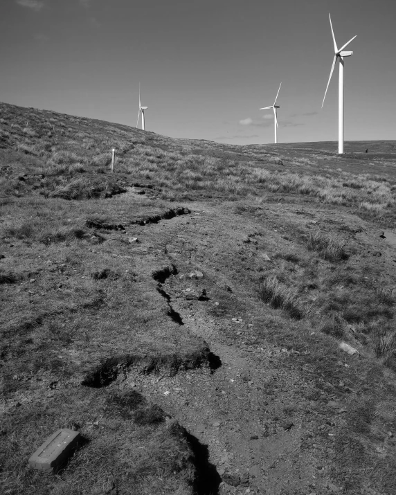 wind farm turbines in black and white on the side of the hill