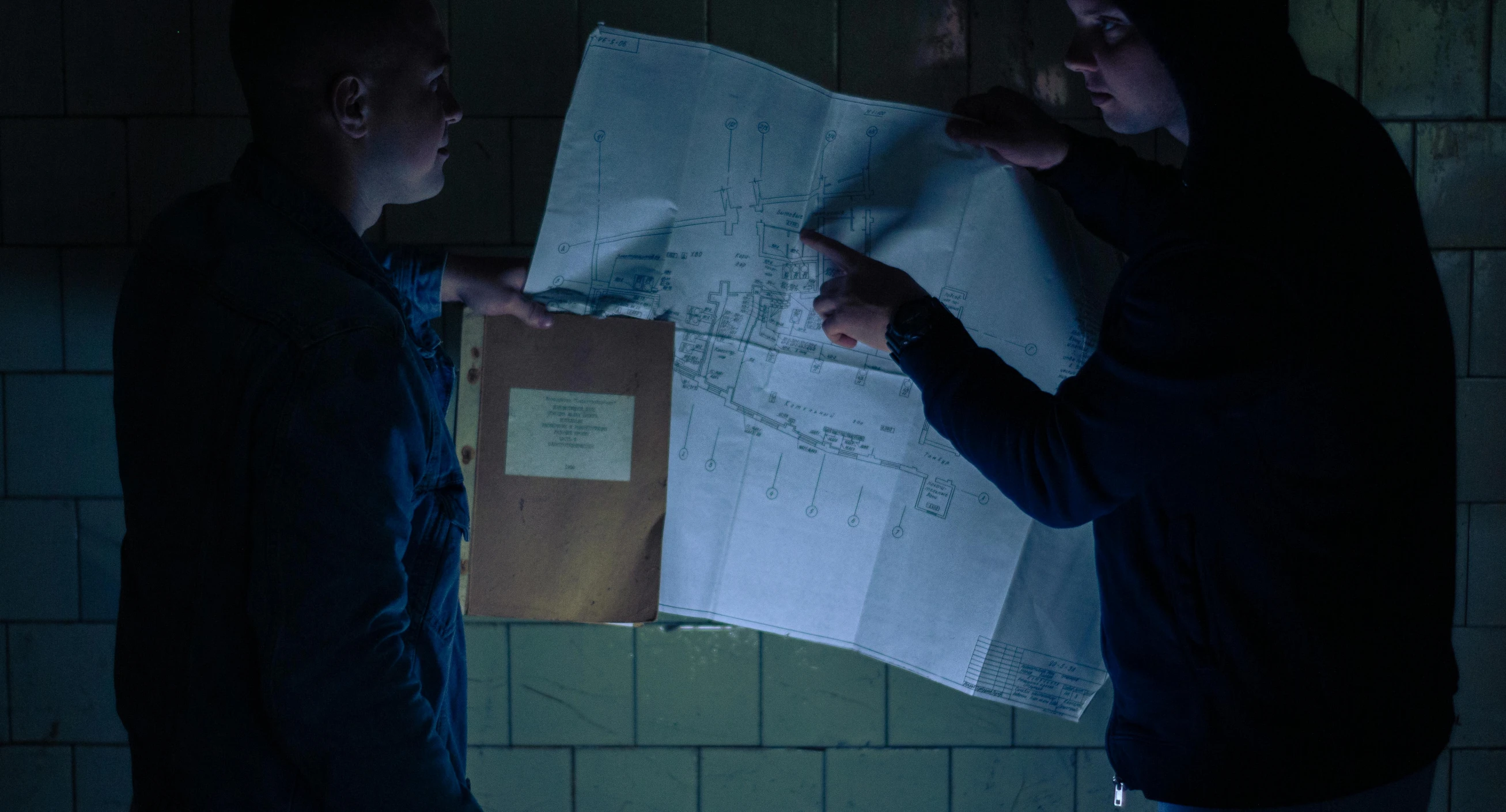 two people with a map in a dimly lit room