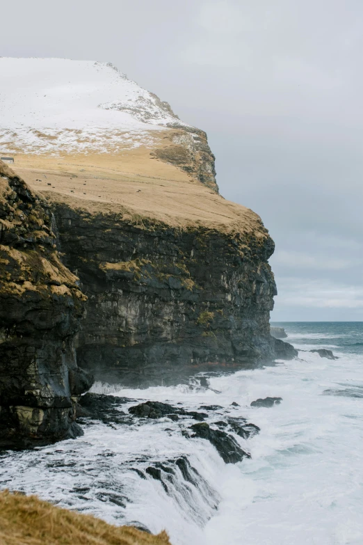 waves crash against the rocky cliff wall near the ocean