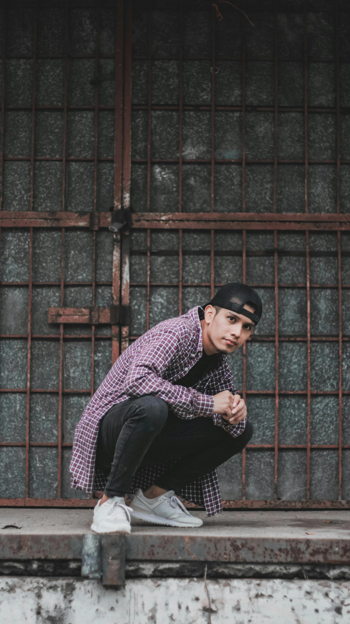 young adult man seated on step leaning against metal structure