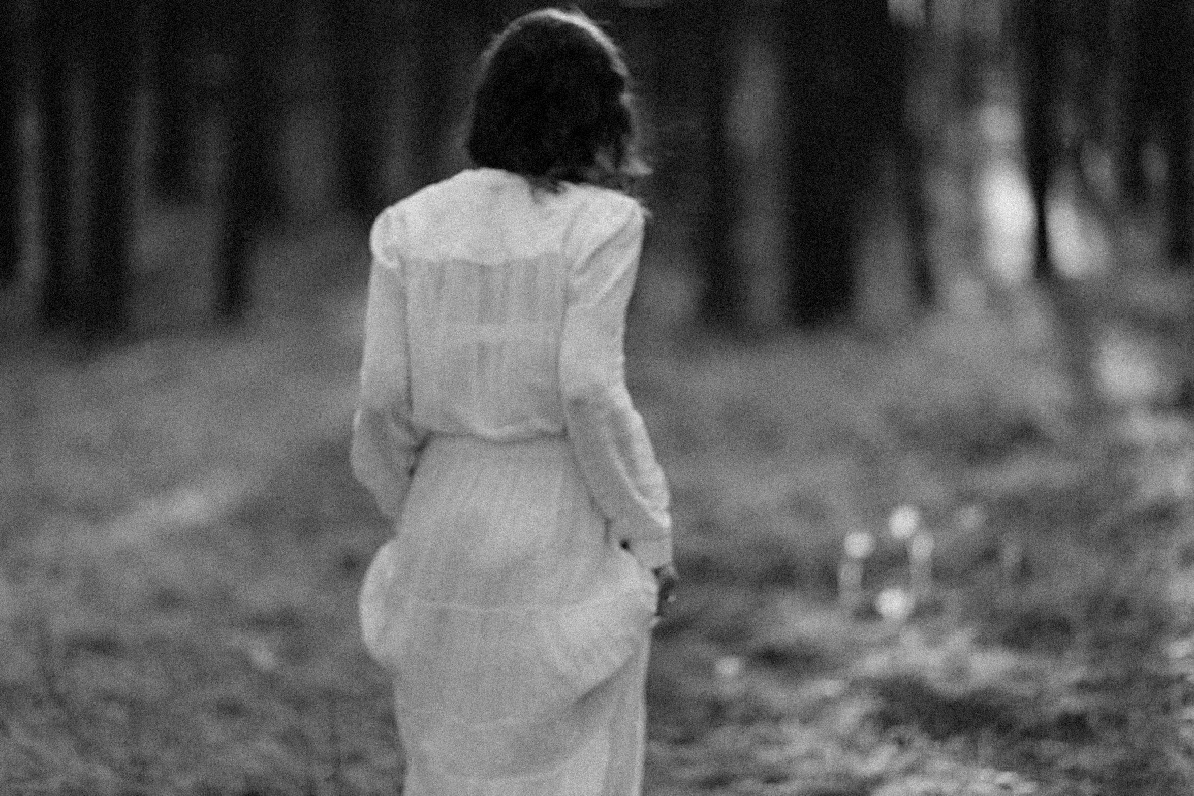 black and white po of a woman walking through the woods