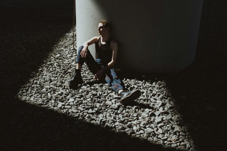 a young man is seated on a stone bed