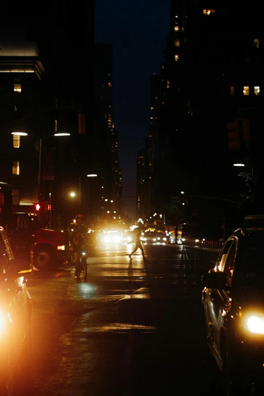 a man riding his bike across the street at night