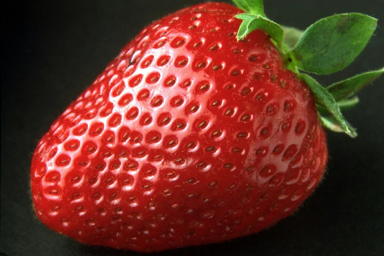 a close up of a ripe strawberry on a black surface