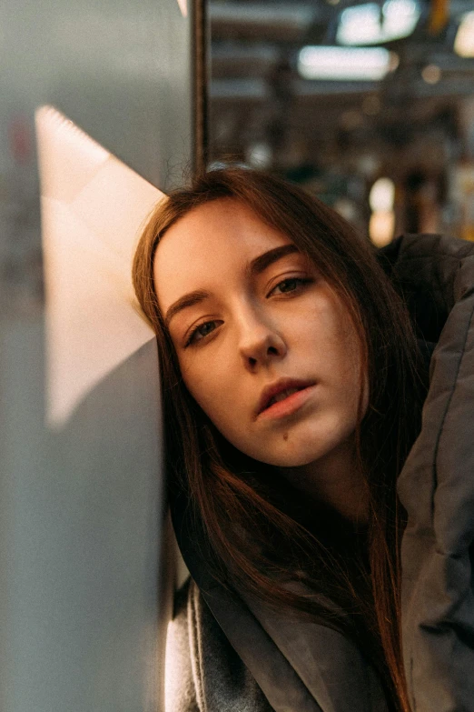 a girl with long hair leaning against a wall