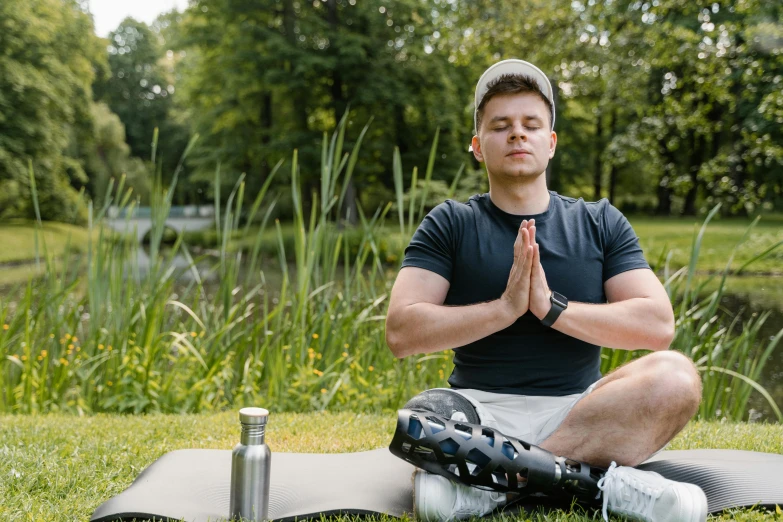 man meditating outside in meditation with a drink