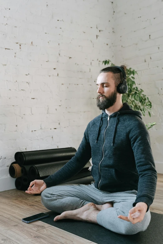 a man sitting on a yoga mat doing exercises with a headset
