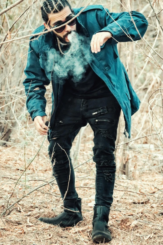 a man with dreadlocks and sunglasses standing in a forest