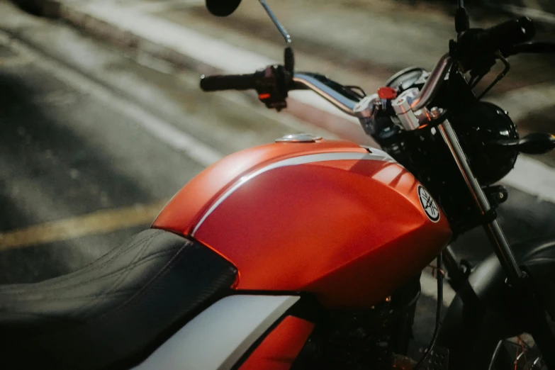 a close up of an orange motorcycle parked on a street