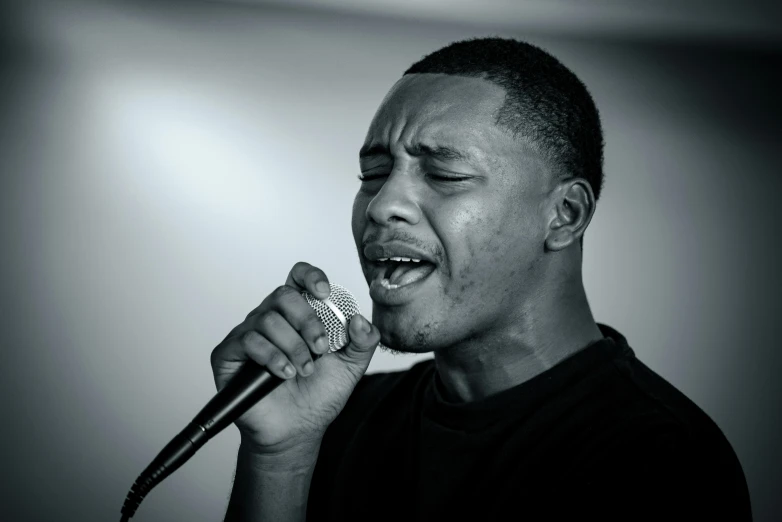 a man singing into a microphone while holding his hand up