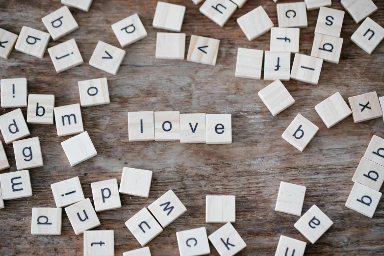 several scrabble tiles on a wood surface spell out the word love