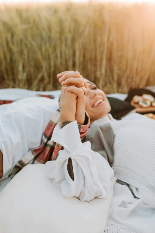 woman laying in a field with a sunset in the background