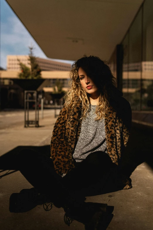 a person sitting on the ground with a animal print jacket