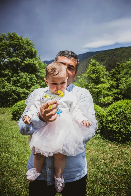 a man holding up his young daughter, in the middle of a field