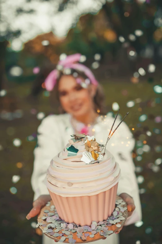 a woman wearing a pink hat and holding a cupcake in her hands