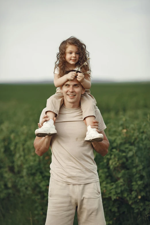 a man and little girl are holding two shoes while standing in a green field