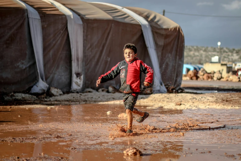 small boy walking through muddy area with water on his feet