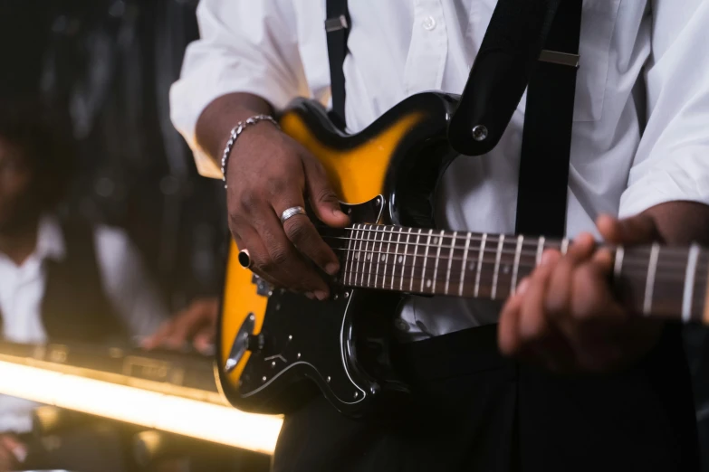 the man in a white shirt is playing a yellow guitar