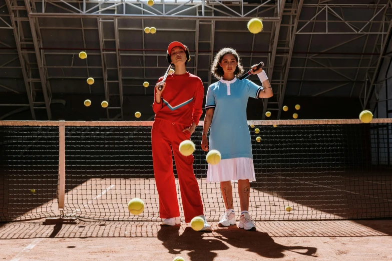 two women playing tennis with balls in the air