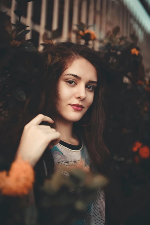 a young woman with long hair standing near some flowers