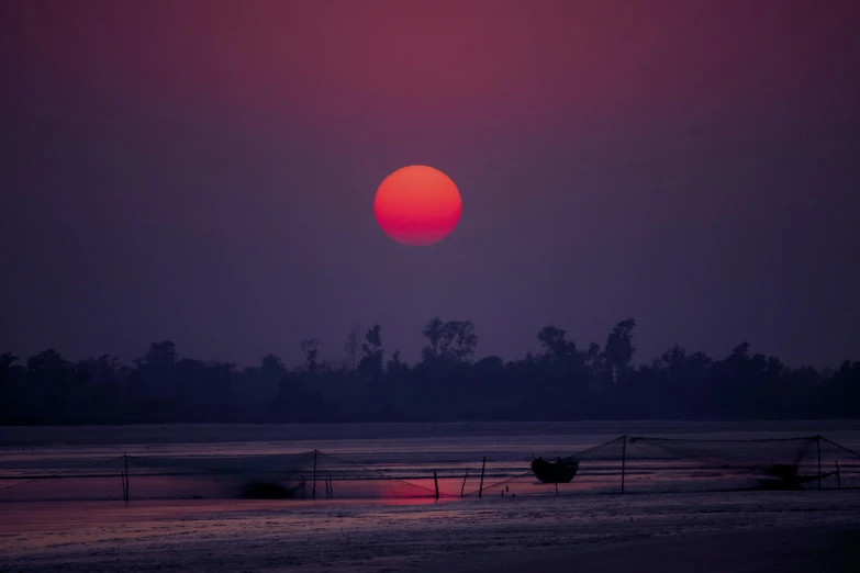 the sun is setting on the beach with boats