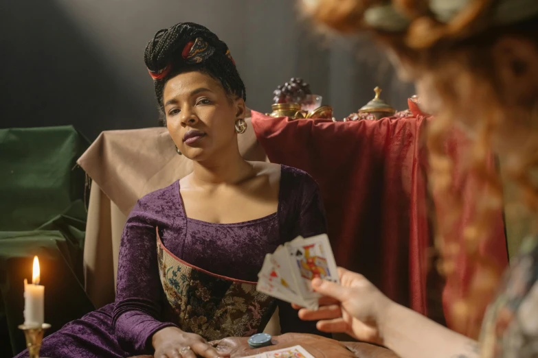 a woman holding cards, while another woman is looking at her phone