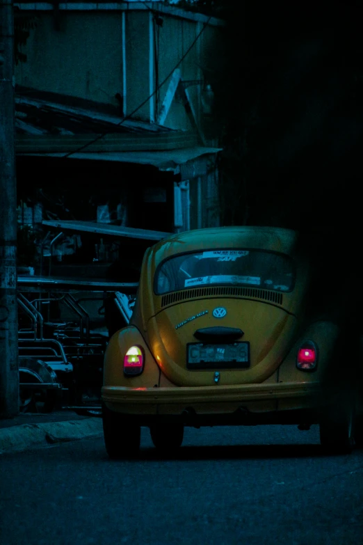 an orange beetle driving on the road in the dark