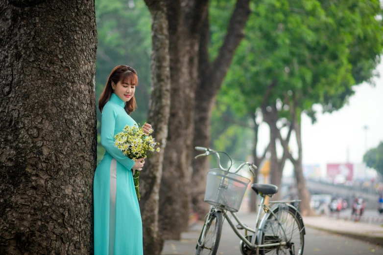 girl in blue dress and bicycle near tree