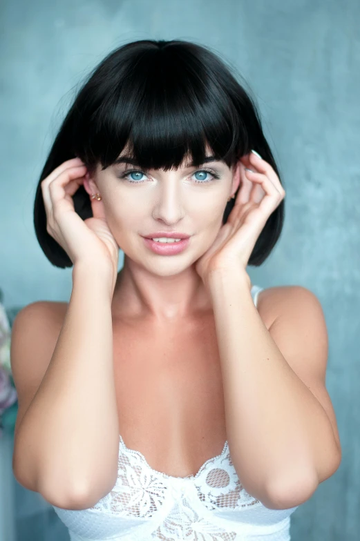 a woman is holding her head with her hand while wearing white