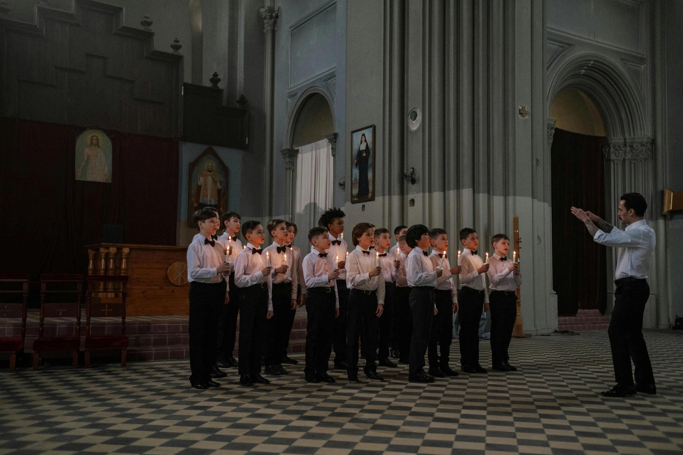 a choir stands in front of candles at a church