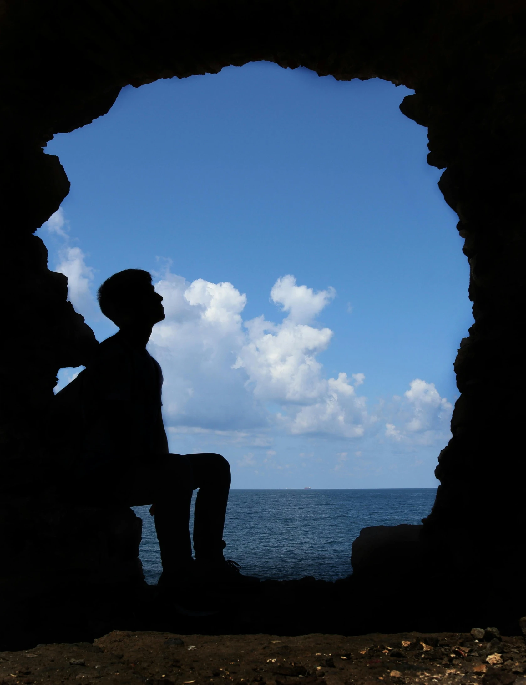 a silhouette of a person sitting down on a rocky beach