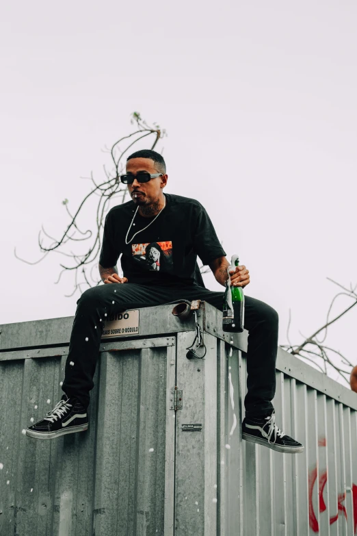 an image of man sitting on the roof drinking a bottle