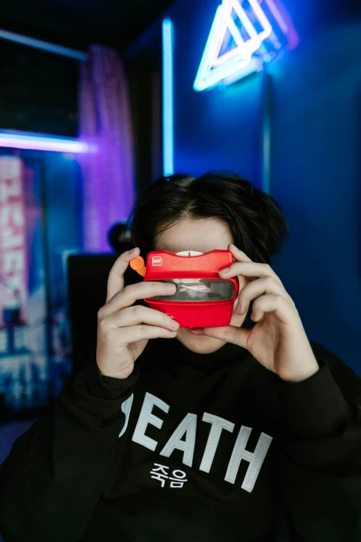 a person in black sweatshirt covering their face with a red case