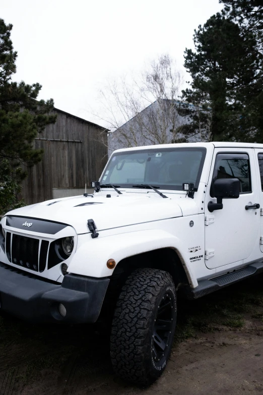 a jeep with the hood up is parked in front of trees